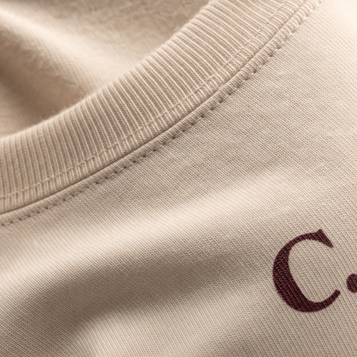 Macro detail of cream cotton and the C. mark below the collar